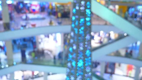 Das Konzept des Weihnachtseinkaufs. Unscharfe Halle in einem riesigen modernen Einkaufszentrum mit vielen Rolltreppen und einem Weihnachtsbaum — Stockfoto