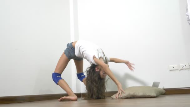 Flexibiliteit en kracht. mooi jong meisje met perfecte lichaam spieren thuis, tijdens het kijken naar de les van stretching online op een laptopcomputer uit te rekken — Stockvideo