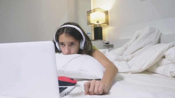 Дівчина-підліток в навушниках шокує те, що відбувається на екрані її ноутбука, тому що вона була сама. концепція безпеки інтернету для дітей — стокове відео
