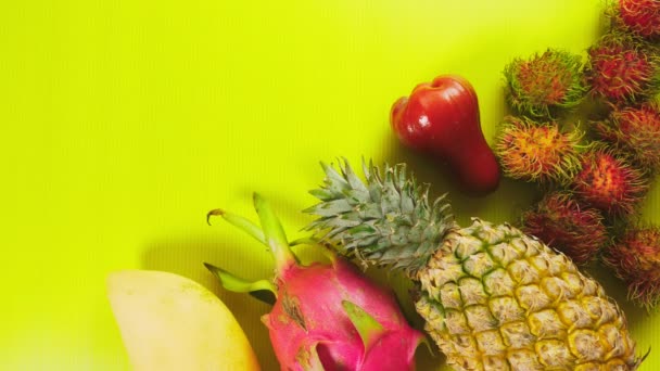 Frutas tropicales sobre un fondo amarillo brillante. Concepto de fruta mínima. espacio de copia — Vídeos de Stock