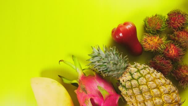 Frutas tropicais em um fundo amarelo brilhante. Conceito mínimo de fruta. espaço de cópia — Vídeo de Stock