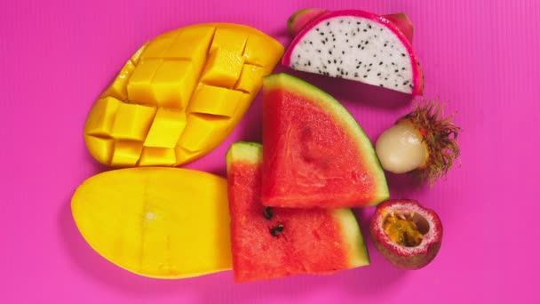 Fruta tropical sobre un fondo rosa brillante. rebanadas Concepto mínimo de fruta . — Vídeos de Stock