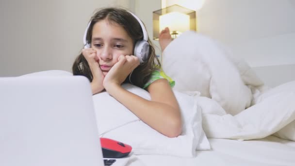 Chica adolescente en los auriculares en shock de lo que está sucediendo en la pantalla de su ordenador portátil, porque ella estaba sola. concepto de seguridad de internet para niños — Vídeo de stock