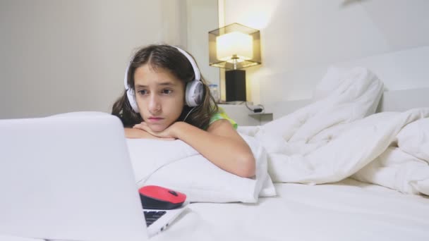 戴耳机的女孩对笔记本电脑屏幕上发生的事情感到震惊 因为她一个人 儿童的网络安全概念 — 图库视频影像