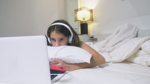 Chica adolescente en los auriculares en shock de lo que está sucediendo en la pantalla de su ordenador portátil, porque ella estaba sola. concepto de seguridad de internet para niños — Vídeo de stock