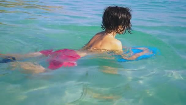 Gros plan. Garçon adolescent nager à bord dans la mer et sourire — Video