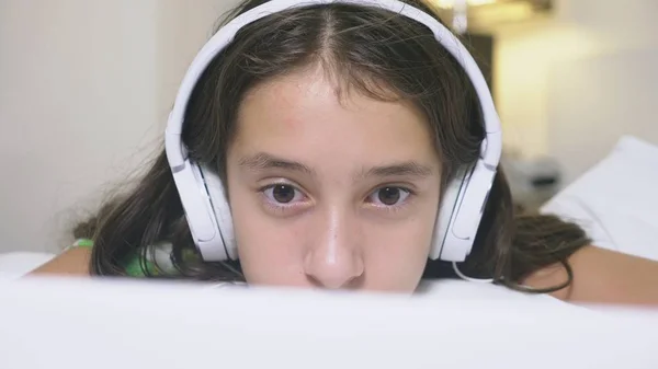 Girl teenager in headphones in shock of what is happening on the screen of her laptop, because she was alone. internet safety concept for kids — Zdjęcie stockowe