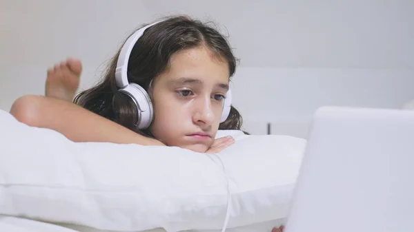 Flicka Tonåring i hörlurar i chock av vad som händer på skärmen på hennes laptop, eftersom hon var ensam. Internet säkerhetskoncept för barn — Stockfoto