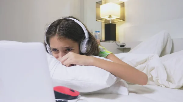 Girl teenager in headphones in shock of what is happening on the screen of her laptop, because she was alone. internet safety concept for kids — Zdjęcie stockowe