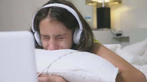 Girl teenager in headphones in shock of what is happening on the screen of her laptop, because she was alone. internet safety concept for kids — Zdjęcie stockowe