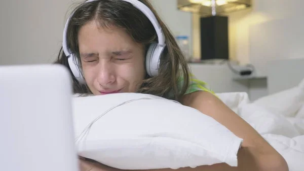Girl teenager in headphones in shock of what is happening on the screen of her laptop, because she was alone. internet safety concept for kids — Zdjęcie stockowe