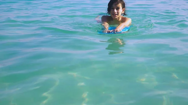 Primer plano. Niño adolescente nadar a bordo en el mar y sonreír — Foto de Stock