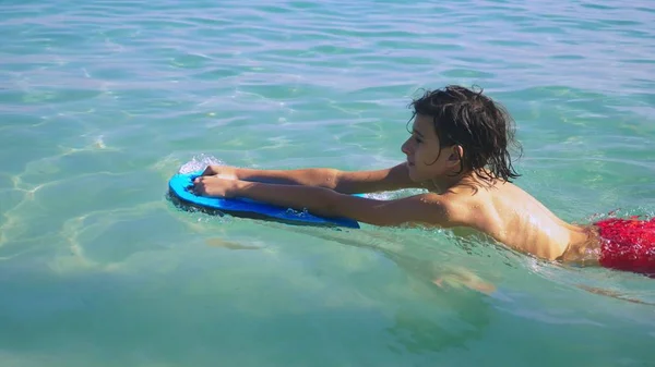Närbild. Pojke tonåringen simma ombord i havet och leende — Stockfoto