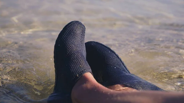 Close-up de pernas femininas em sapatos pretos para nadar no fundo da água do mar transparente — Fotografia de Stock