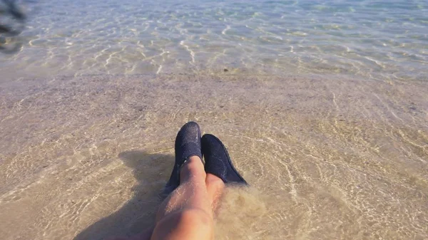 Close-up de pernas femininas em sapatos pretos para nadar no fundo da água do mar transparente — Fotografia de Stock