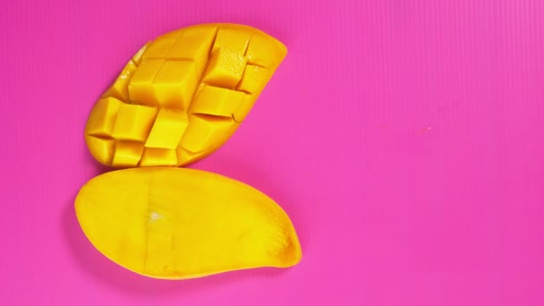 Female hands pick up the yellow mango from a bright pink background. Minimal fruit concept. — Stock Video