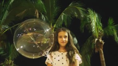mutlu genç kız büyük havadar, parlayan balon palmiye ağaçları arka planı onun elinde tutan. akşam saat. Turizm ve plaj tatil kavramı.