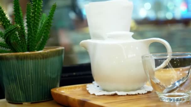 Liten kaktus och tekanna på ett bord på ett café vid fönstret — Stockvideo