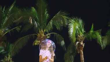 mutlu genç kız büyük havadar, parlayan balon palmiye ağaçları arka planı onun elinde tutan. akşam saat. Turizm ve plaj tatil kavramı.