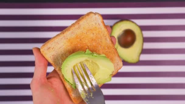 Abacate em pão torrado com especiarias em um fundo branco preto listrado. O conceito de alimentação saudável . — Vídeo de Stock