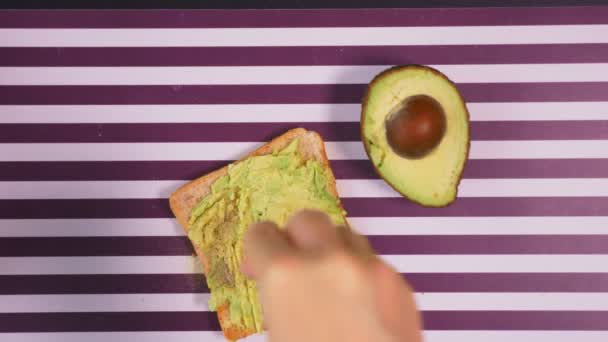 Avocado op een toast brood met kruiden op een gestreept zwart witte achtergrond. Het begrip van gezond eten. — Stockvideo