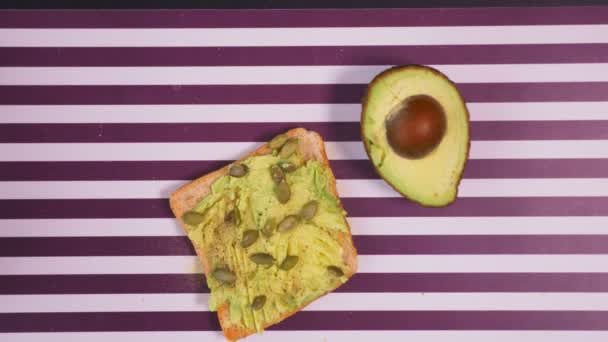 Авокадо на хлебе со специями на полосатом черно-белом фоне. Концепция здорового питания . — стоковое видео