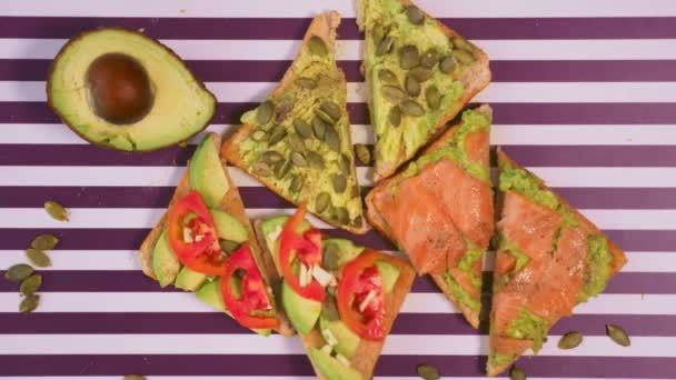 Avocado op een toast brood met kruiden op een gestreept zwart witte achtergrond. Het begrip van gezond eten. — Stockvideo