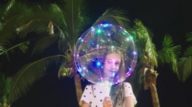 mutlu genç kız büyük havadar, parlayan balon palmiye ağaçları arka planı onun elinde tutan. akşam saat. Turizm ve plaj tatil kavramı