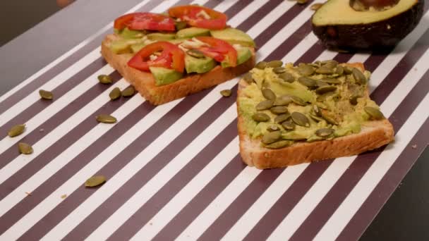 Avocado op een toast brood met kruiden op een gestreept zwart witte achtergrond. Het begrip van gezond eten. — Stockvideo