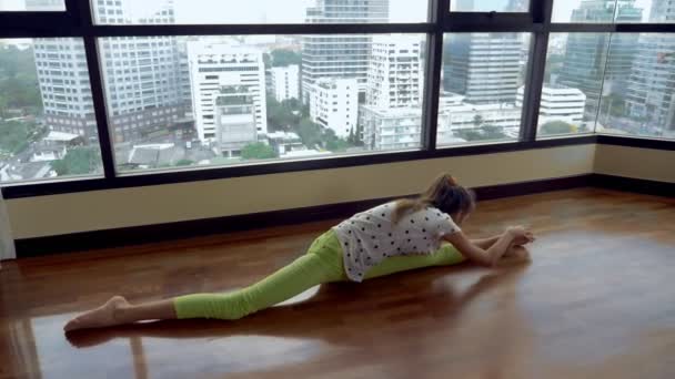 苗条的年轻女孩伸展在一个大的全景窗口前俯瞰摩天大楼 — 图库视频影像