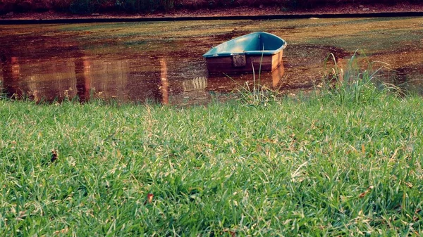 Um velho barco abandonado no meio de um rio sujo — Fotografia de Stock