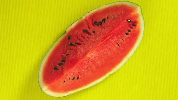 Kvinnliga händer sätta en bit vattenmelon på en ljus gul bakgrund. Minimal frukt koncept. — Stockfoto