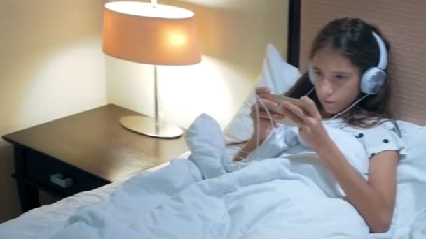 Teen flicka användning smartphone på sängen innan hon sover på natten. Mobila missbrukare koncept. — Stockvideo