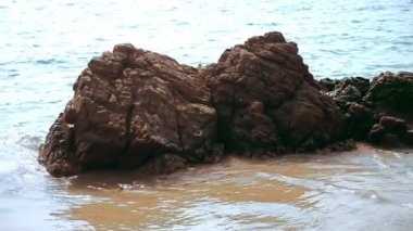 deniz dalgaları tarafından yıkanmış kum plajındaki taş
