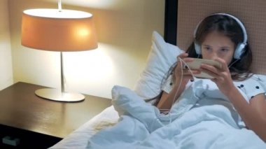 Genç kız kullanma smartphone geceleri uyur önce yatakta. Telefon bağımlısı kavramı.