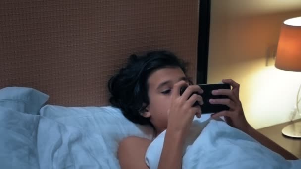Teen pojke använder smartphone på sängen innan sömn på natten. Mobila missbrukare koncept. — Stockvideo