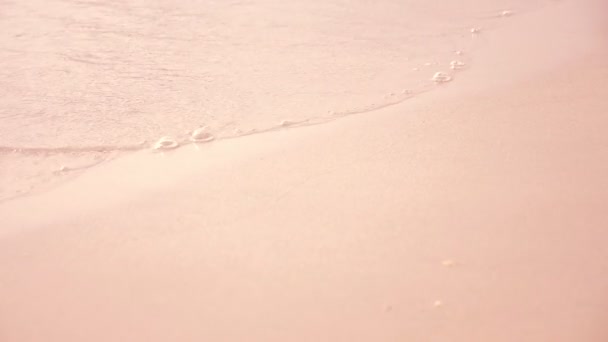 Strand Hintergrund mit Meereswelle bei Sonnenuntergang, Wasser rosa lackiert. die Textur des Sandes. zarte Pastellfarben. Entspannte Atmosphäre — Stockvideo