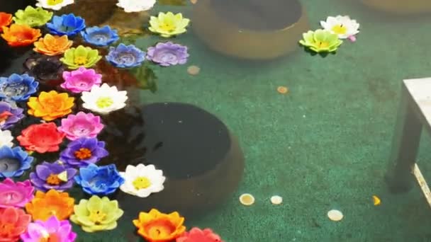 Velas de aroma multicoloridas na forma de uma flor de lótus em uma tigela com água para oferendas ao Buda . — Vídeo de Stock