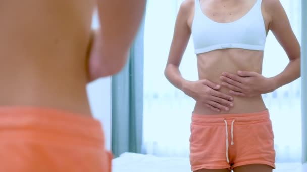 Anorexia concept - slanke tiener meisje, met uitstekende ribben kijken naar haar spiegelbeeld in de spiegel — Stockvideo