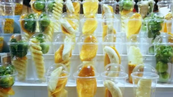 Concept asiatique de street food. Thaïlande. fruits en tasses, tranchés pour faire des smoothies sur le support d'un kiosque extérieur . — Video