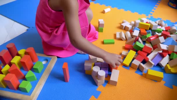 Pequeña chica linda asiática jugando cubos, sentado en un piso de color. El concepto de desarrollo infantil . — Vídeo de stock