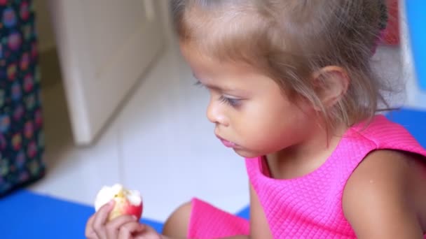 Kleine süße asiatische Mädchen isst einen Apfel — Stockvideo
