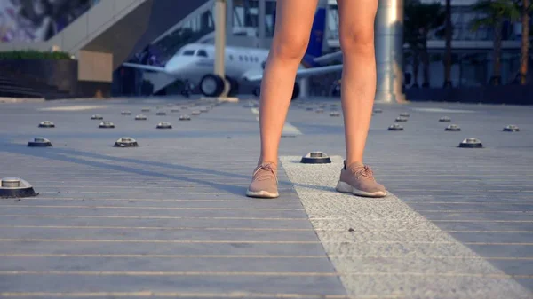 Le concept de tourisme. Femme touriste en lunettes de soleil avec un sac à dos sur le dos va à l'aéroport sur le fond de l'avion. femme blonde souriant à l'aéroport — Photo