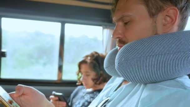 Ein junger Mann mit einem Reisekissen im Auto benutzt ein Smartphone. Straßenverkehrskonzept — Stockvideo