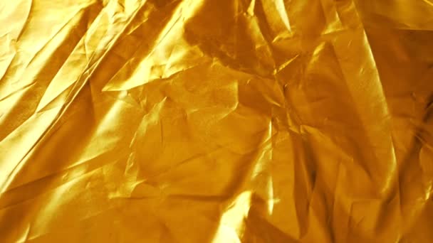 Sfondo di tessuto dorato sintetico accartocciato. primo piano. trama del tessuto. tessuto riflettente la luce — Video Stock