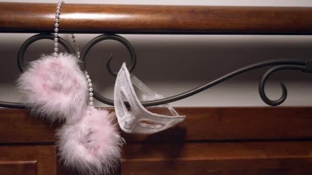 Fur handcuffs and lace mask on the forged headboard. close-up — Stock Video