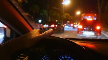 bulanıklık, birinci şahıs görünümü. arabanın direksiyonuna el. bir gece şehir yolunda trafikte sürüş. cam üzerinde yağmur damlaları