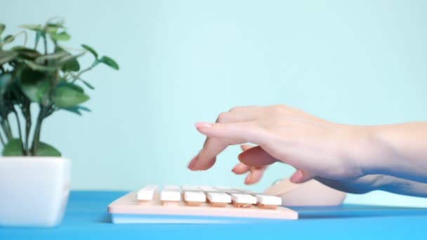 Primo piano. elegante scheda video di auguri. mani femminili stanno digitando su una tastiera rosa, accanto a un fiore. su sfondo blu . — Video Stock