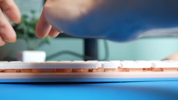 Close-up. Vista em primeira pessoa. Mãos femininas digitando em um teclado rosa mensagens em redes sociais, contra o fundo de uma tela de computador borrada — Vídeo de Stock