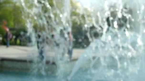 Городской фонтан струи воды на размытом фоне с людьми ходить вокруг фонтанов в центре города . — стоковое видео